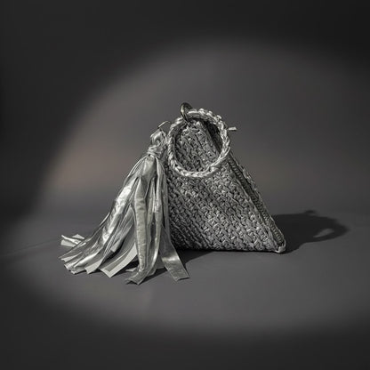 Silver upcycled t-shirt yarn crochet pyramid clutch with tassel on grey backdrop